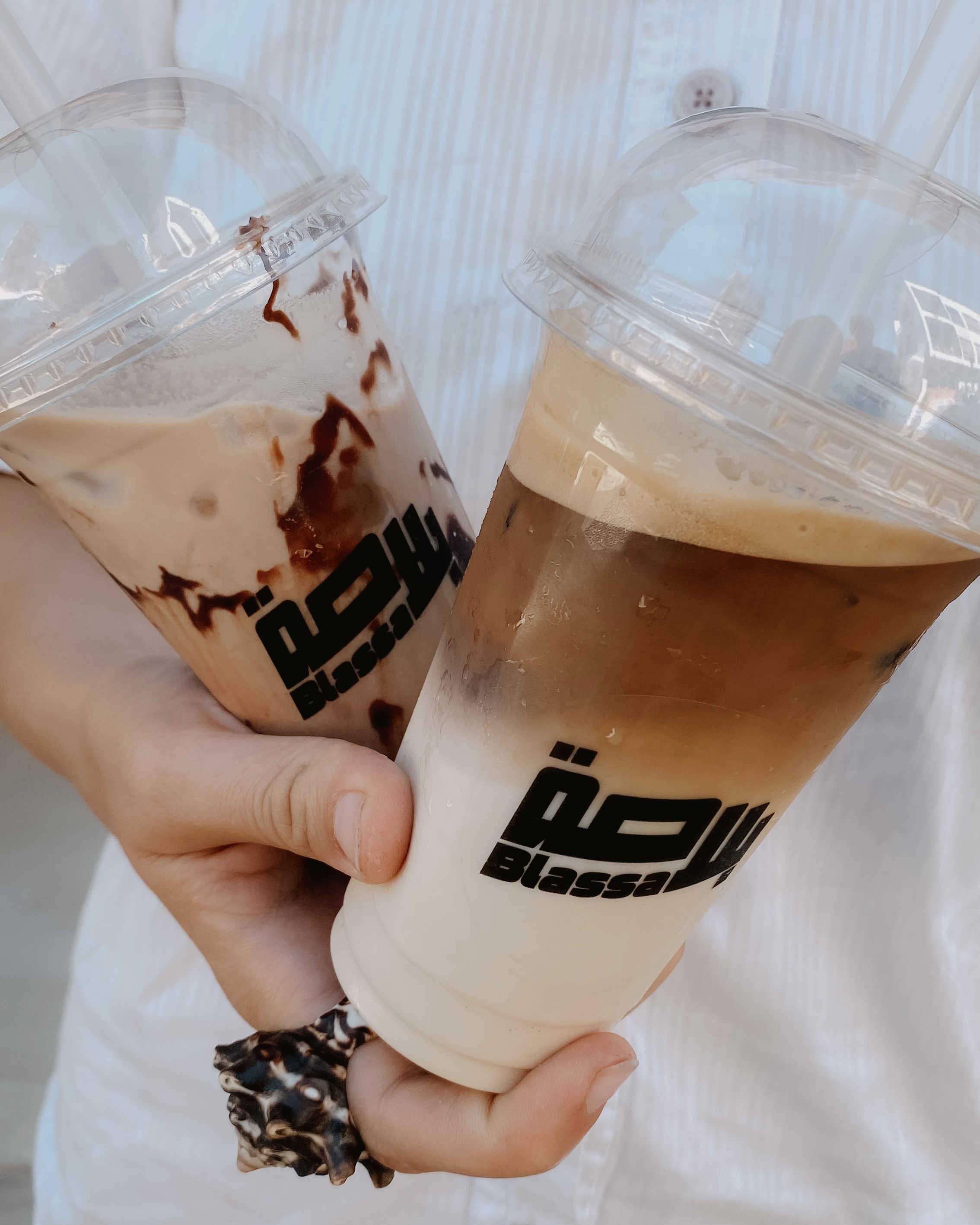 Espresso poured from a steel pitcher into an iced milk coffee in a Blassa cup tucked into a jeans pocket